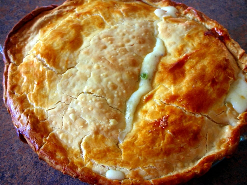 Whole baked Chicken Pot Pie in pie pan on a brown counter top 