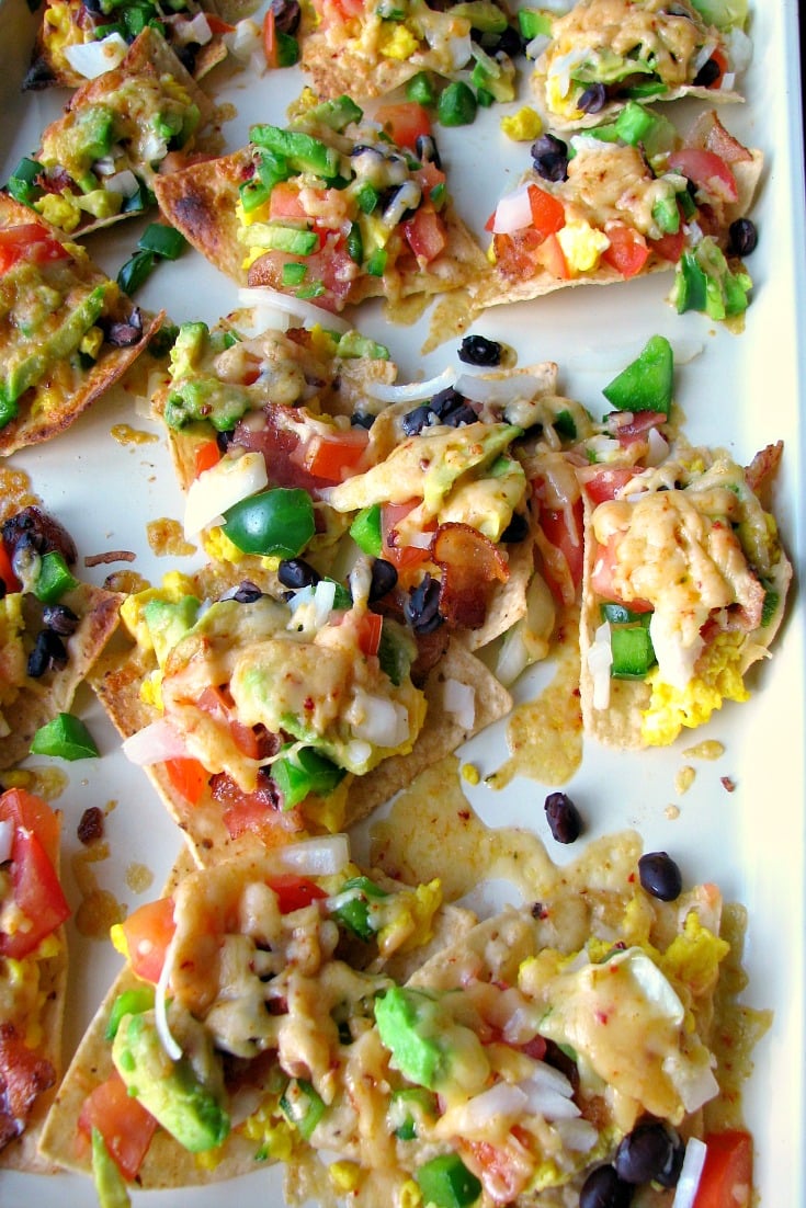 These Cheesy Breakfast Nachos are topped with scrambled eggs, bacon, tomatoes, bell peppers, onions, chipotle cheddar, and black beans. Great for brunch, or a party!