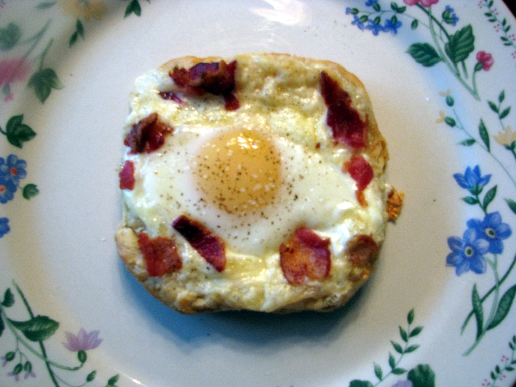 Photo of puff pastry round topped with sunny side up egg bacon and melted cheese