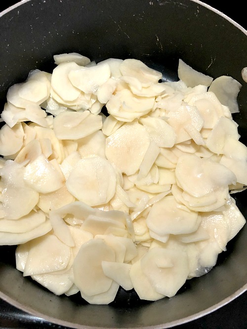 photo of a pot filled with thinly sliced potatoes
