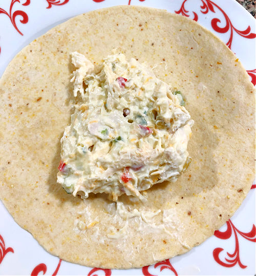 chicken mixture spread on the middle of a tortilla laying on a plate