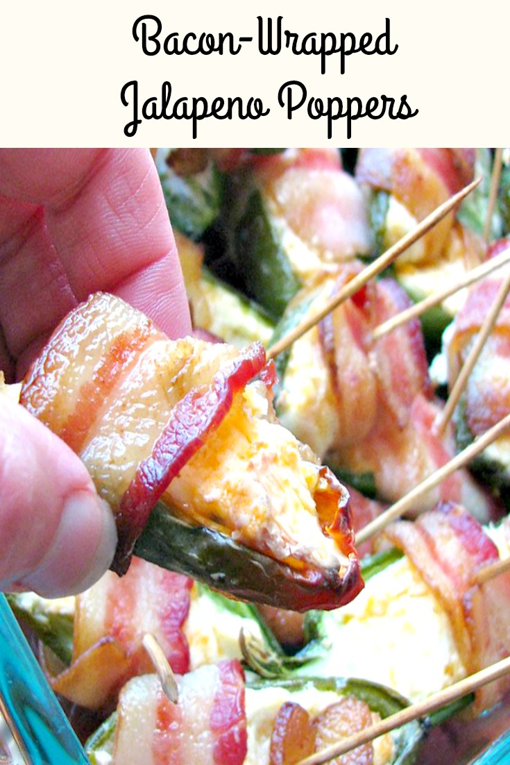Close up photo of a hand holding a Bacon Wrapped Jalapeno Popper with a pan of poppers in the background 