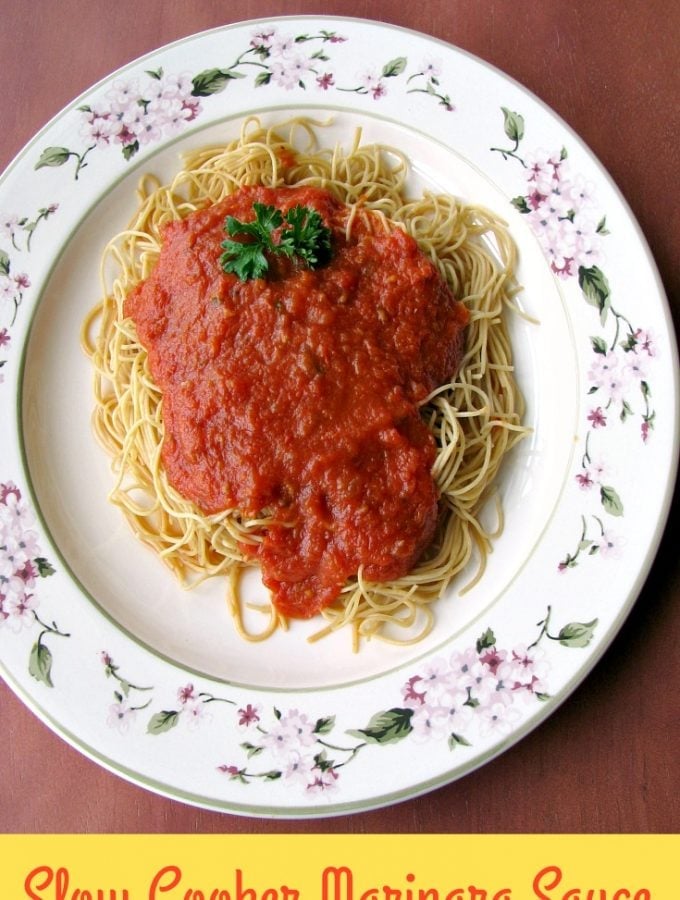 photo of a white flower trimmed plate topped with cooked spaghetti and Slow Cooker Marinara Sauce