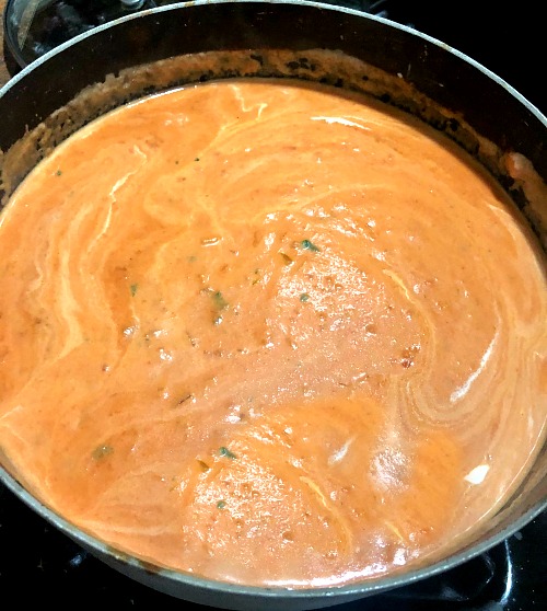 photo of cream mixed into tomato vodka sauce in a pot 