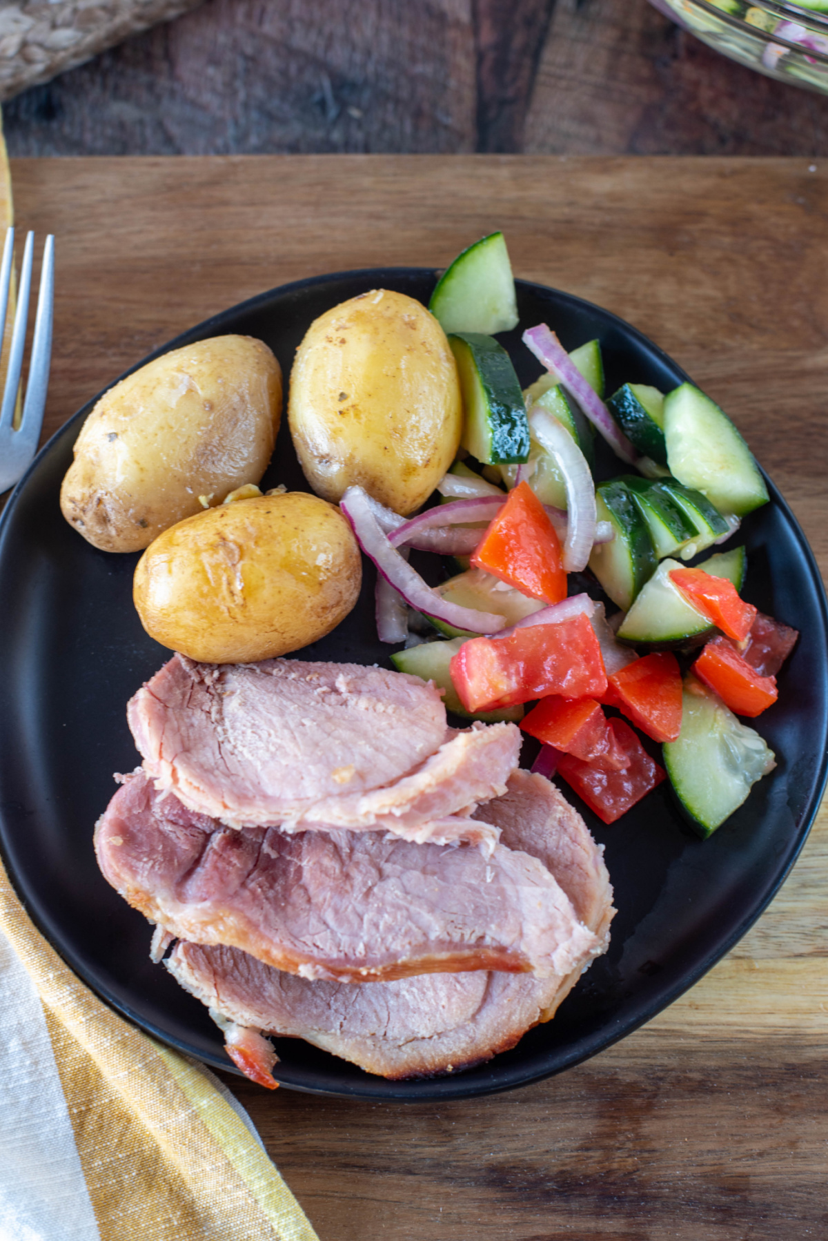 ham potatoes and a salad on a black plate