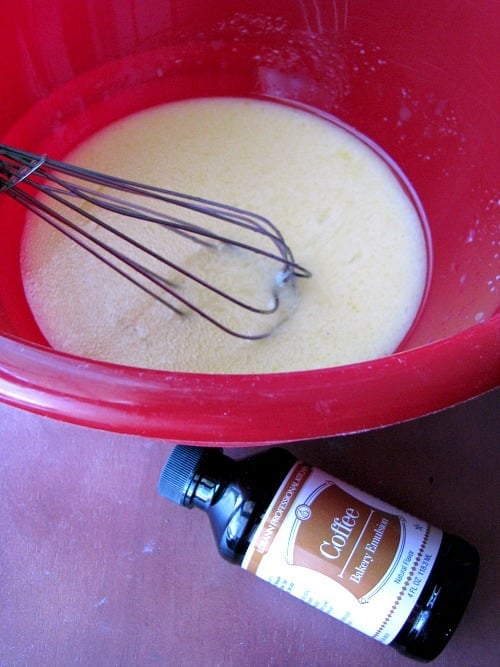 Photo of LorAnn Coffee Flavored Bakery Emulsion next to a red bowl with melted butter and sugar mixed together with a wire whisk