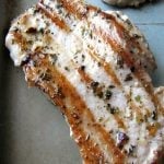 Close-up photo of one Garlic Herb Grilled Pork Chop on a silver baking pan