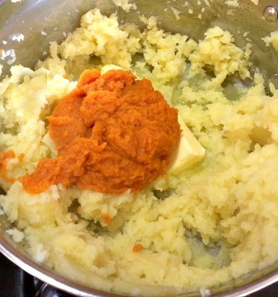 Photo of lightly whipped potatoes in a pot with softened butter and pumpkin puree 