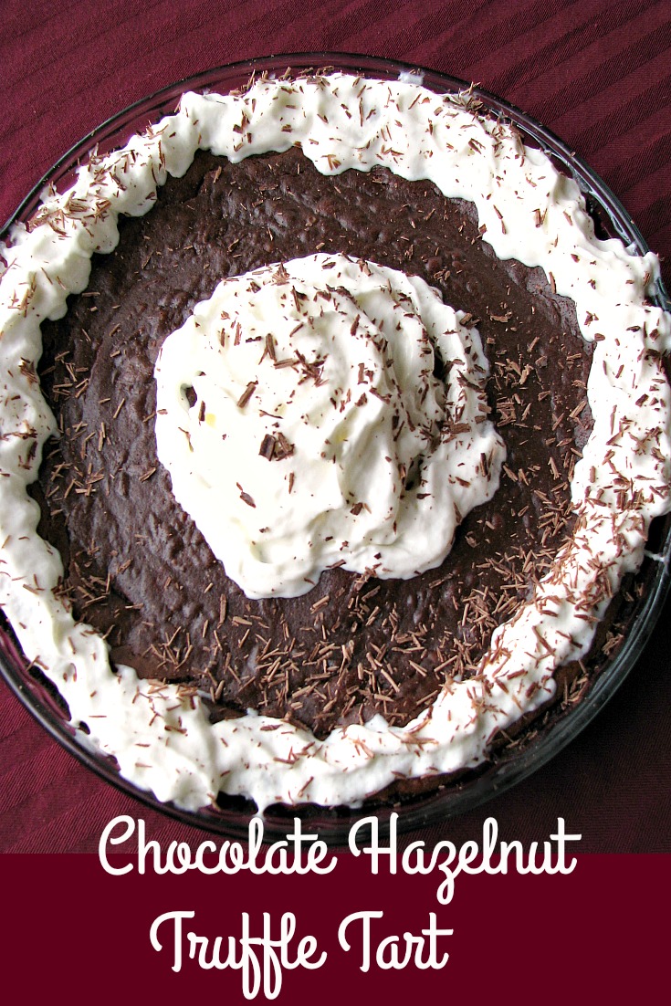 Photo of a whole Chocolate Hazelnut Truffle Tart topped with whipped cream and shaved chocolate 