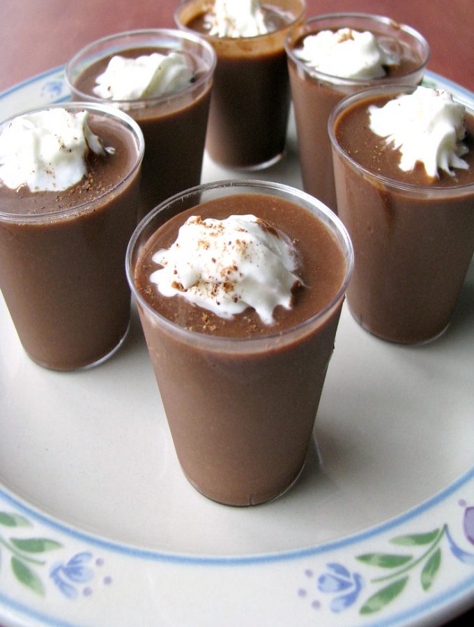 Close up photo of Chocolate Eggnog Pudding Shots on a white plate with flower trim