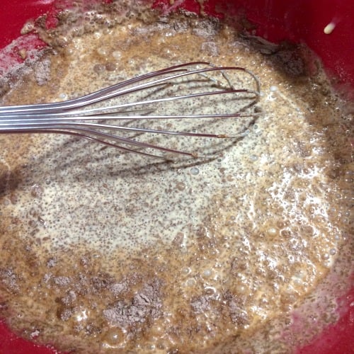 Photo of a mixing bowl with a whisk stirring pudding mix eggnog rum and chocolate liqueur 