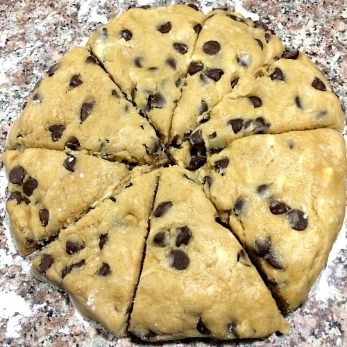 Photo of round dough for Peanut Butter Chocolate Chip Scones cut into almost equal slices 