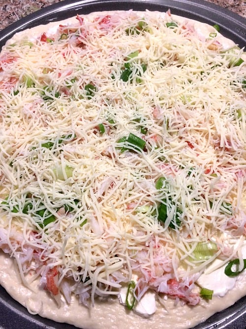 Photo of crab rangoon pizza topped with shredded cheese 