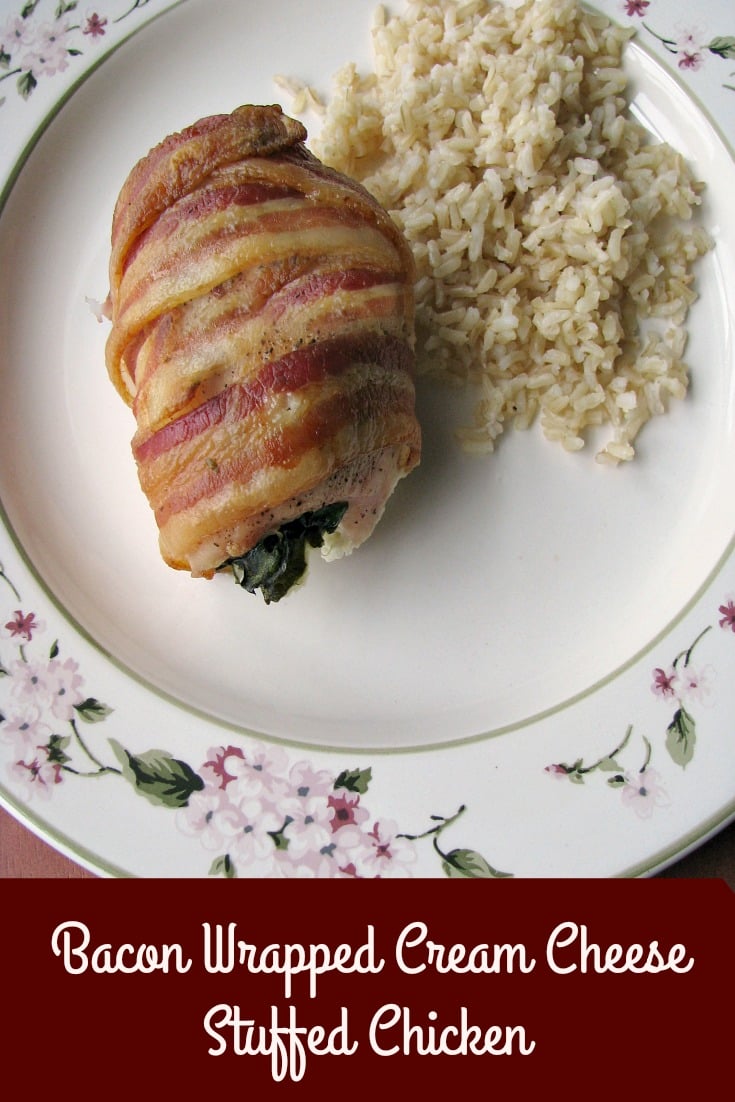 Photo of baked Bacon Wrapped Cream Cheese Stuffed Chicken on a white flower trimmed plate next to brown rice