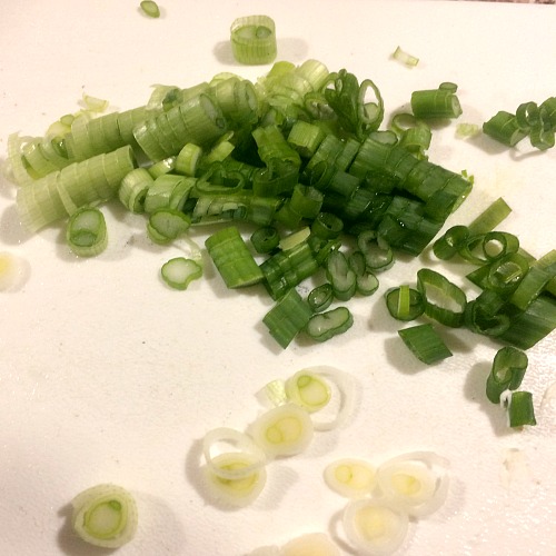 Photo of sliced scallions on a white cutting board 