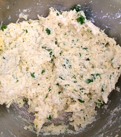 Photo of ricotta mixed with chopped parsley, cheese blend, and spices in a metal bowl 