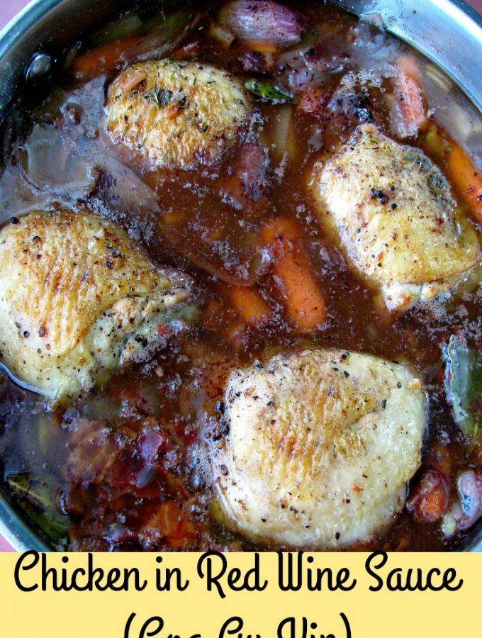 Photo of cooked chicken in red wine sauce showing four chicken thighs in a deep aluminum pan