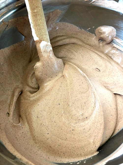 photo of cocoa mixture combined with whipped cream in a metal mixing bowl