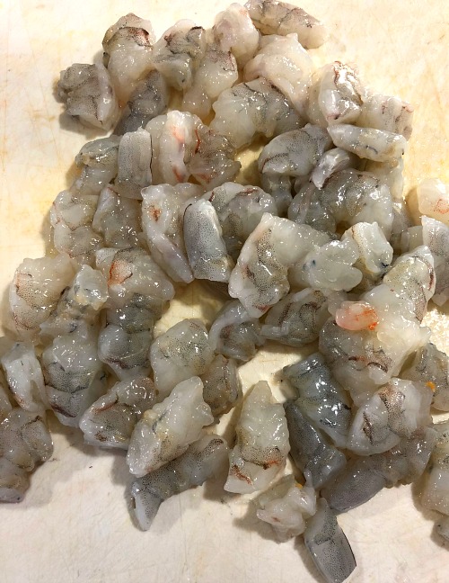 Photo of raw chopped shrimp on a white cutting board