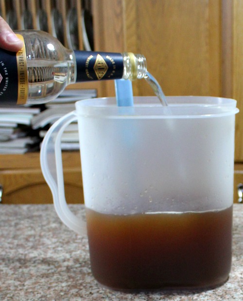 photo of grain alcohol being poured into a beverage pitcher half filled with tea mixture