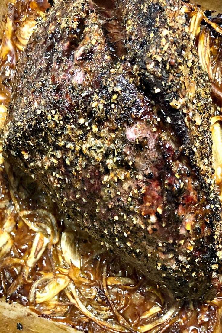 close up photo of roast beef in a baking pan with roasted onions 