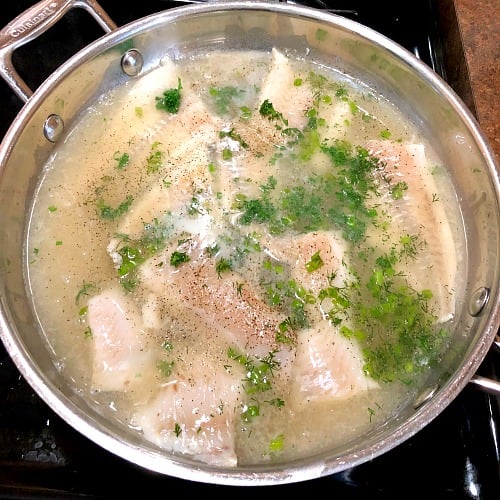 photo of haddock simmering on a stovetop 