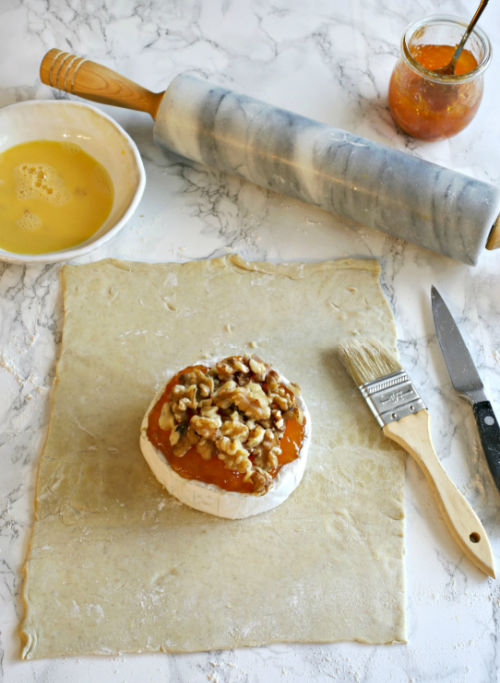 photo of cheese topped with walnuts and apricot preserves on top of puff pastry dough
