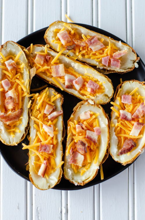 potatoes topped with bacon and cheese on a black plate 