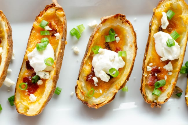 potato skins topped with sour cream on a white platter