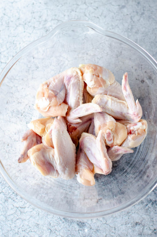 photo of raw chicken wings in a clear glass bowl
