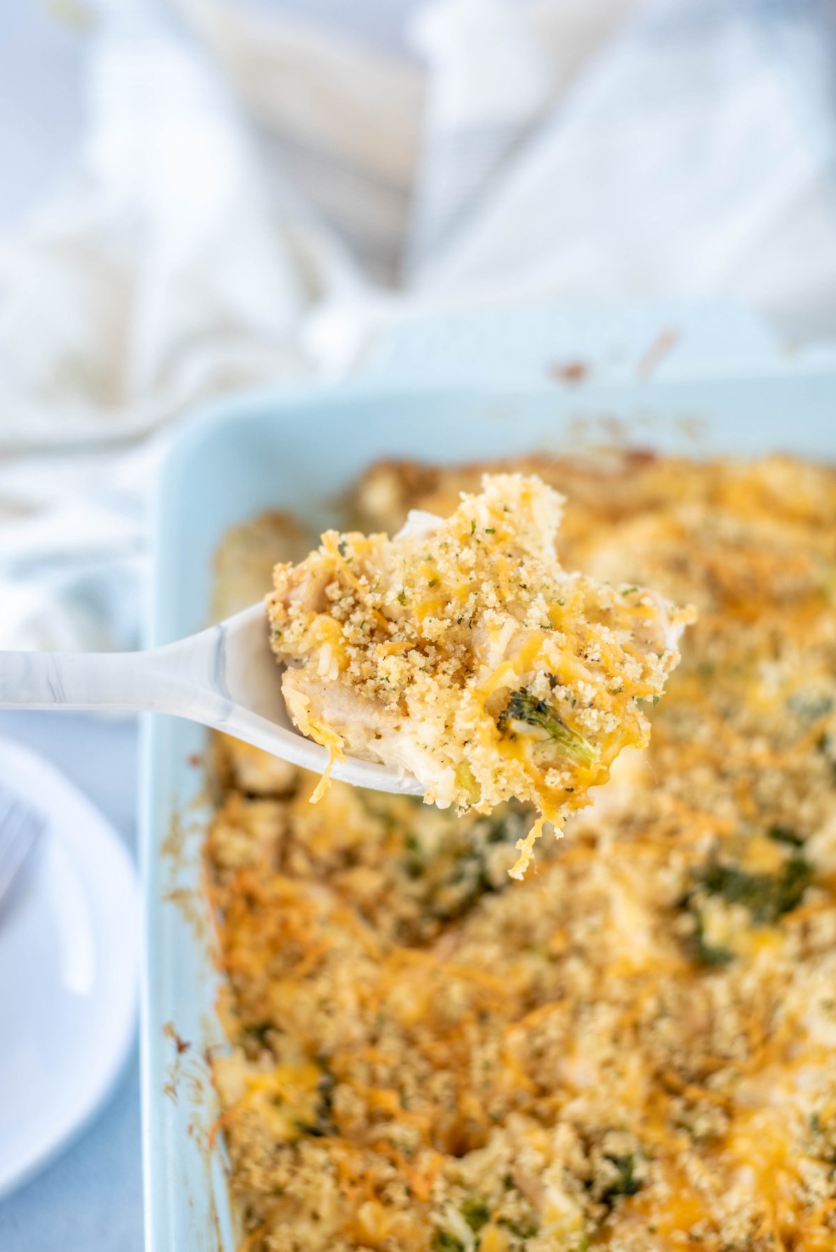 baked casserole on a serving spoon held over a baking dish